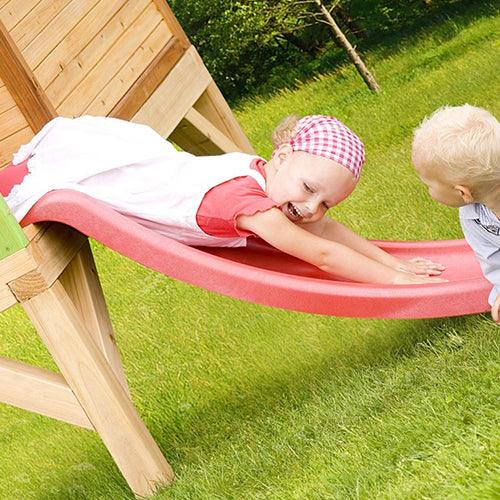 kind-glijd-van-glijbaan-houten-speelhuis-tom-van-axi